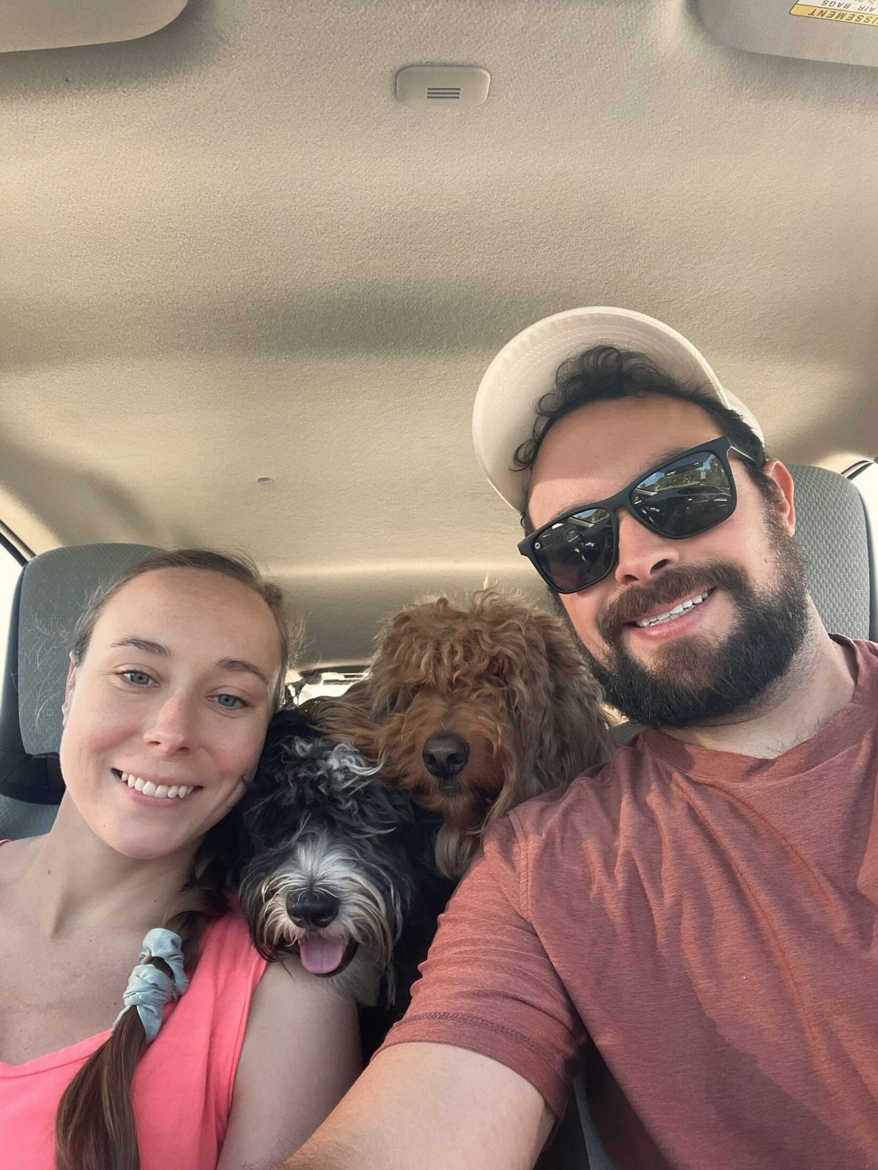 Sam Solomon and a woman with light-brown hair take a car selfie with Otto and Remi between them