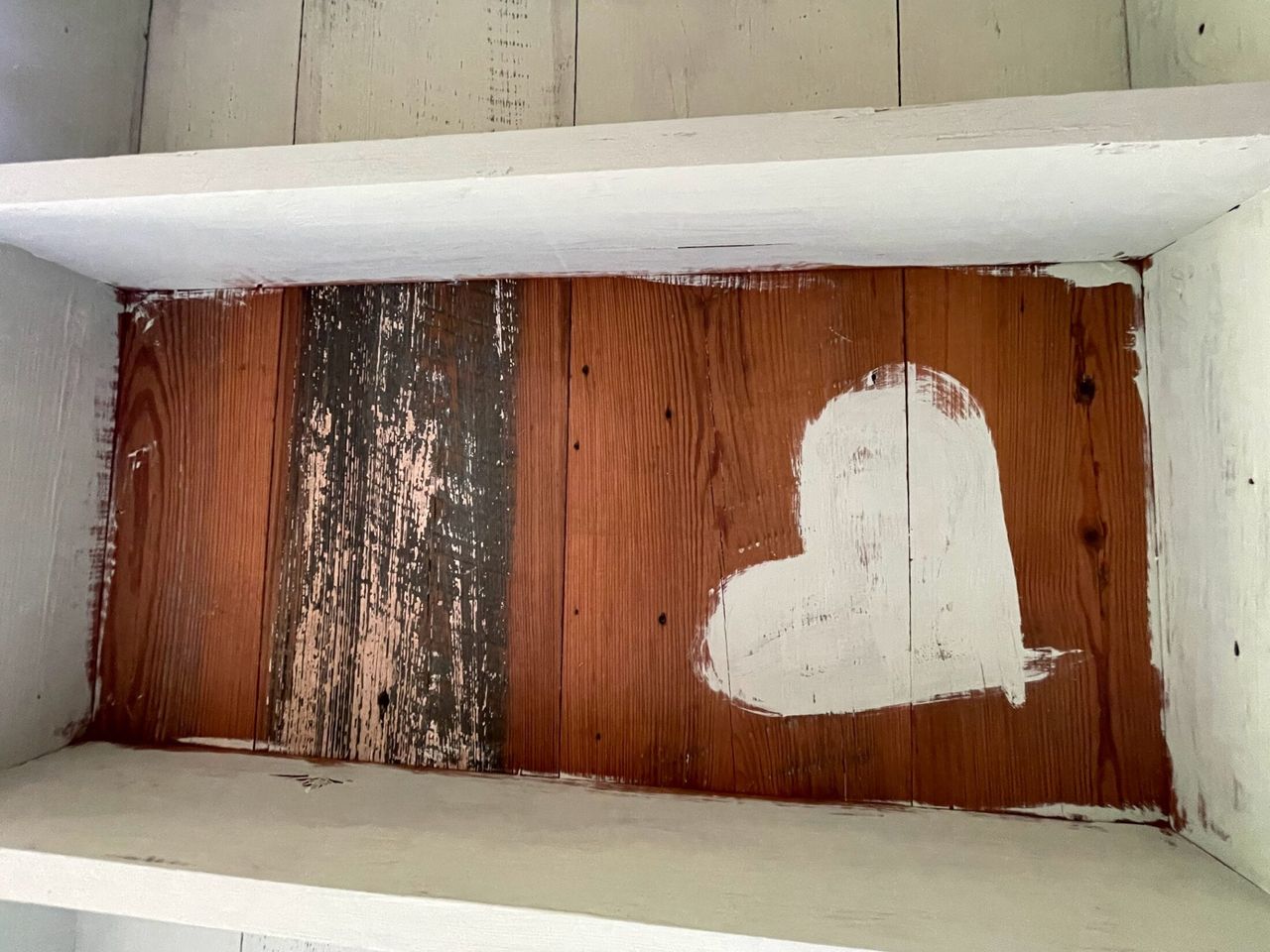 Wooden shelf interior with rustic wood planks and a white painted heart on the back panel