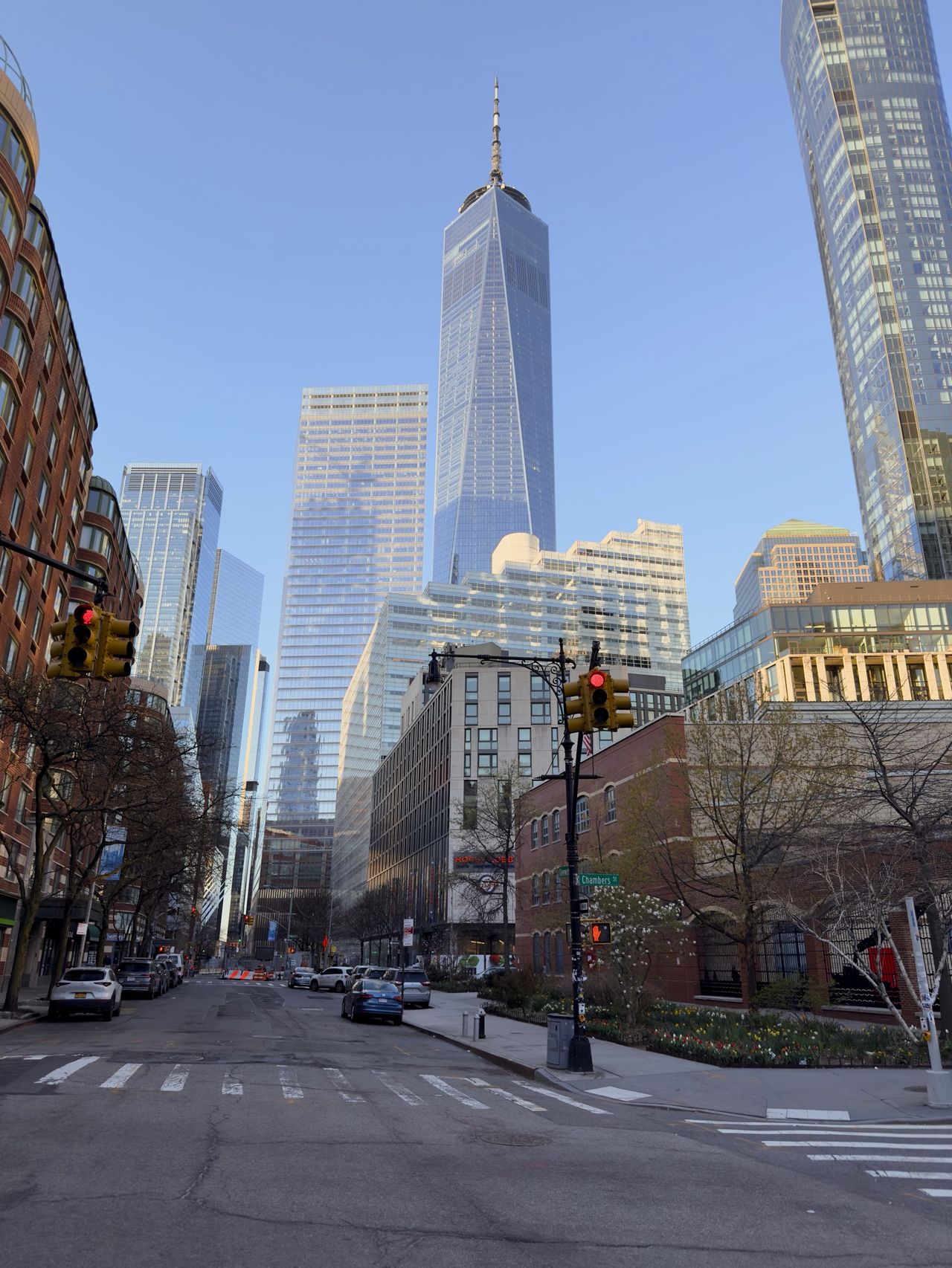 One World Trade Center seen from several blocks away, framed by a quiet intersection and traffic signals.