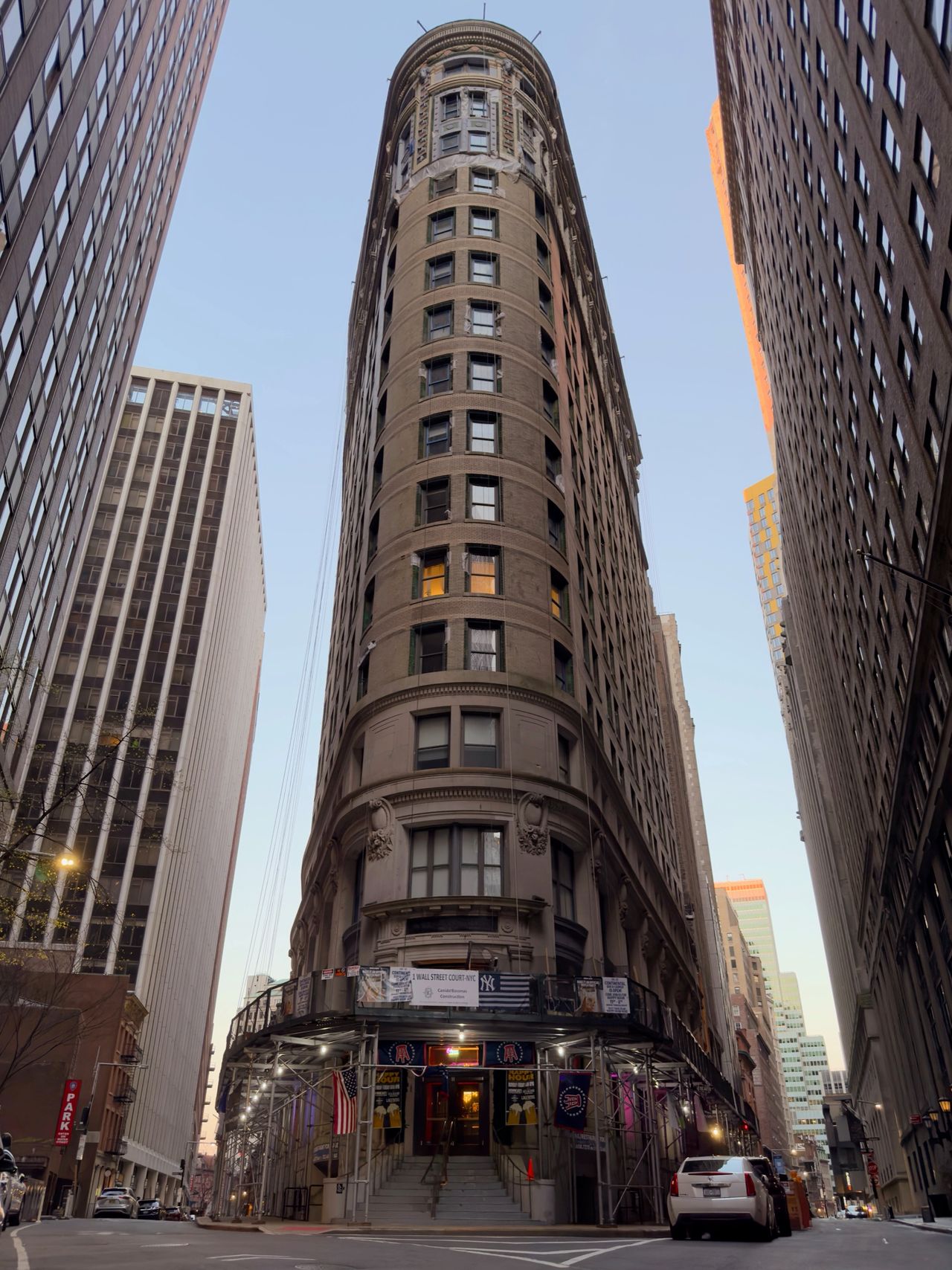 A street-level view of a rounded historic tower framed by tall office buildings.