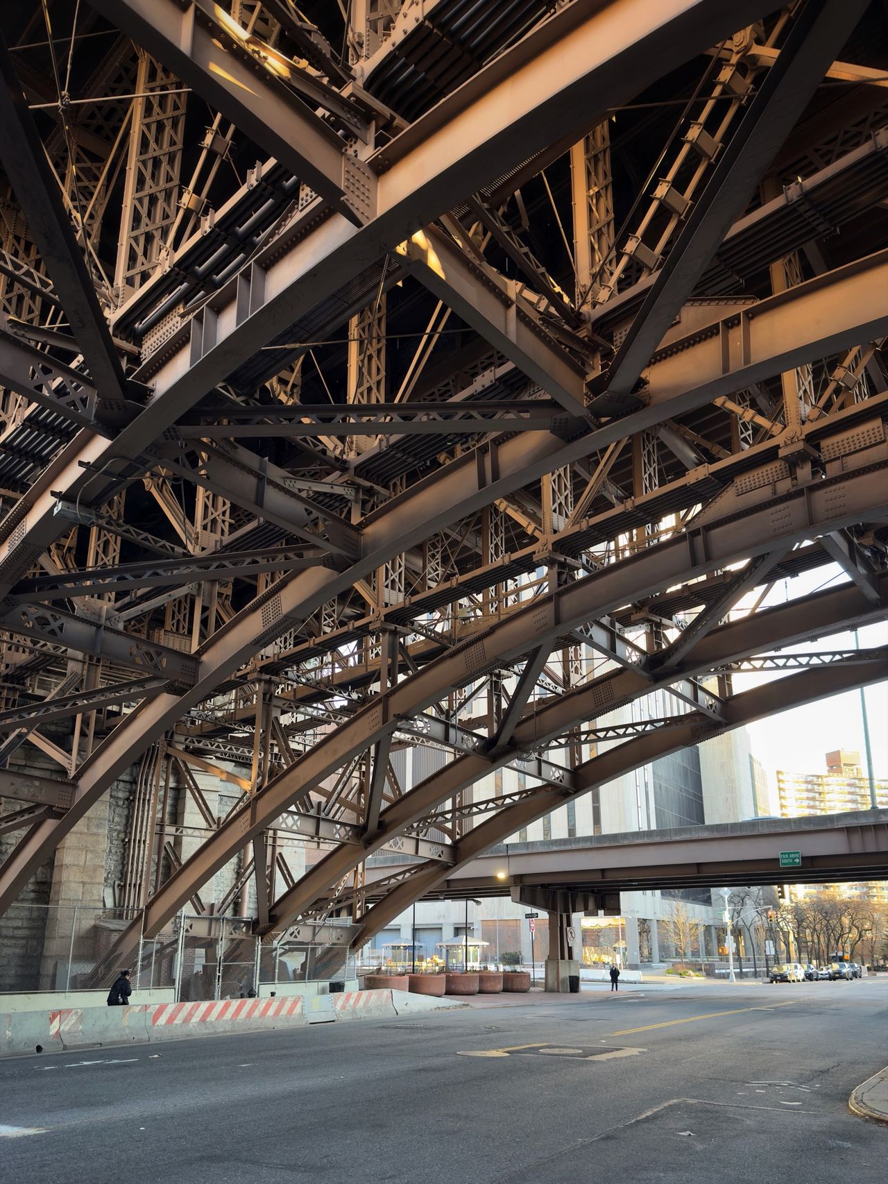 The intricate iron lattice and arched trusses of a bridge approach seen from directly below.