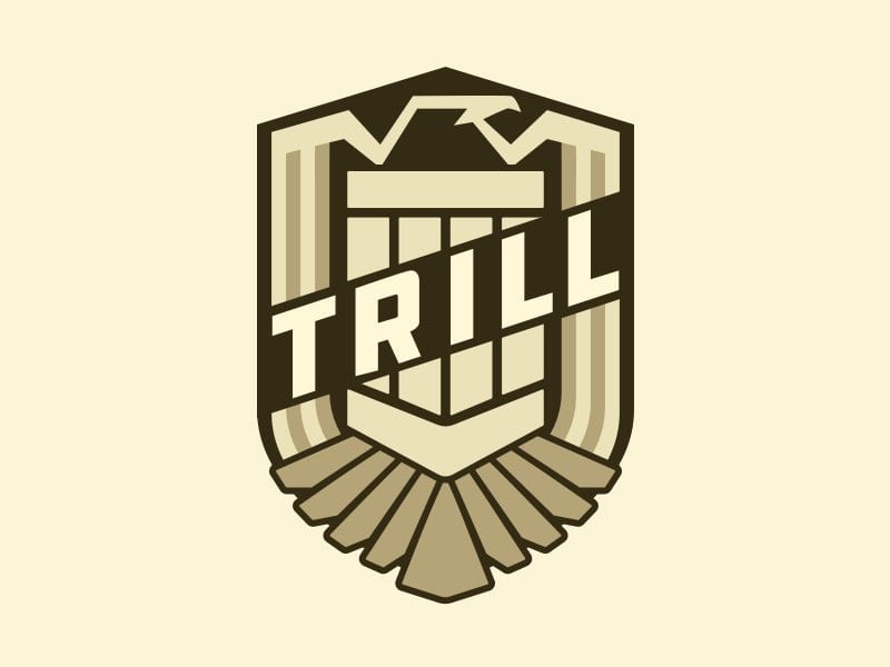 Shield-shaped badge with an eagle and the word TRILL in cream and dark brown
