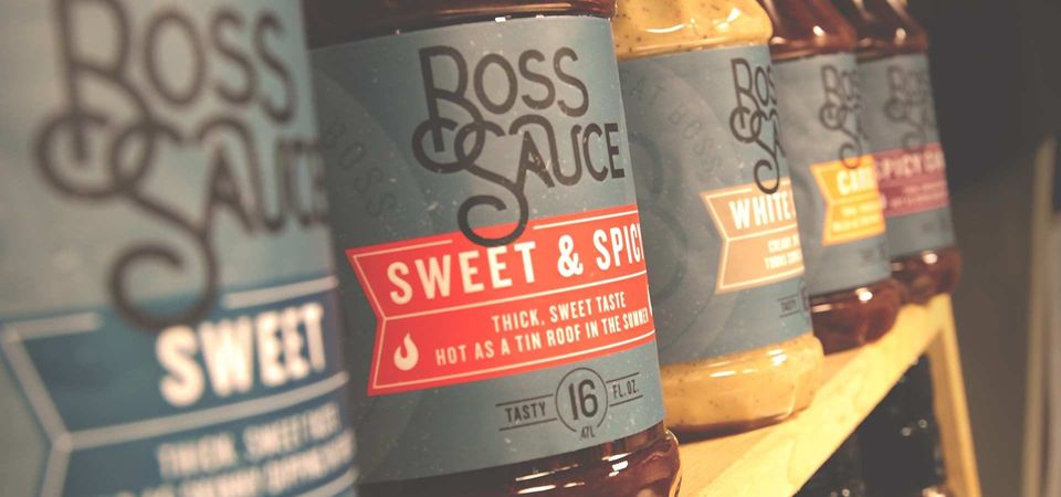 Row of Boss Sauce BBQ bottles on a shelf including Sweet, Sweet & Spicy and White