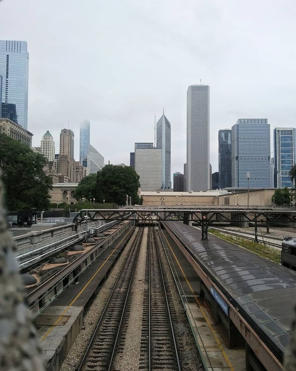 Rail tracks at Van Buren Street station leading toward the Chicago skyline on a gray day