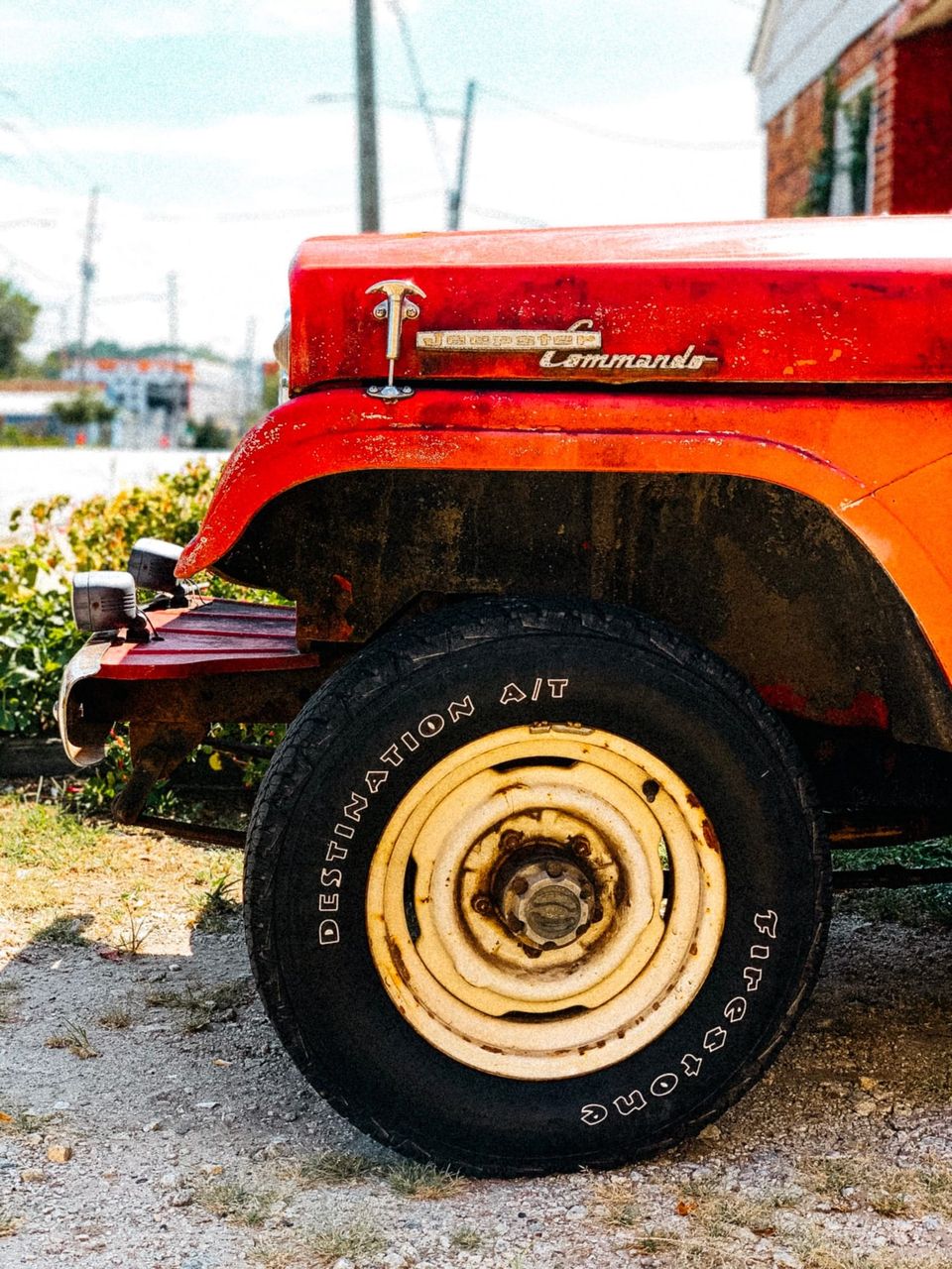 Jeepster Commando hood badge above a Firestone Destination A/T tire on a cream wheel