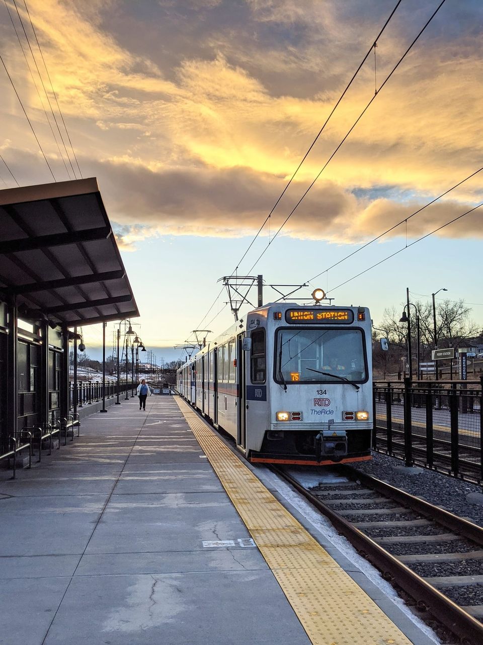 RTD light rail train signed Union Station at a platform under golden sunset clouds
