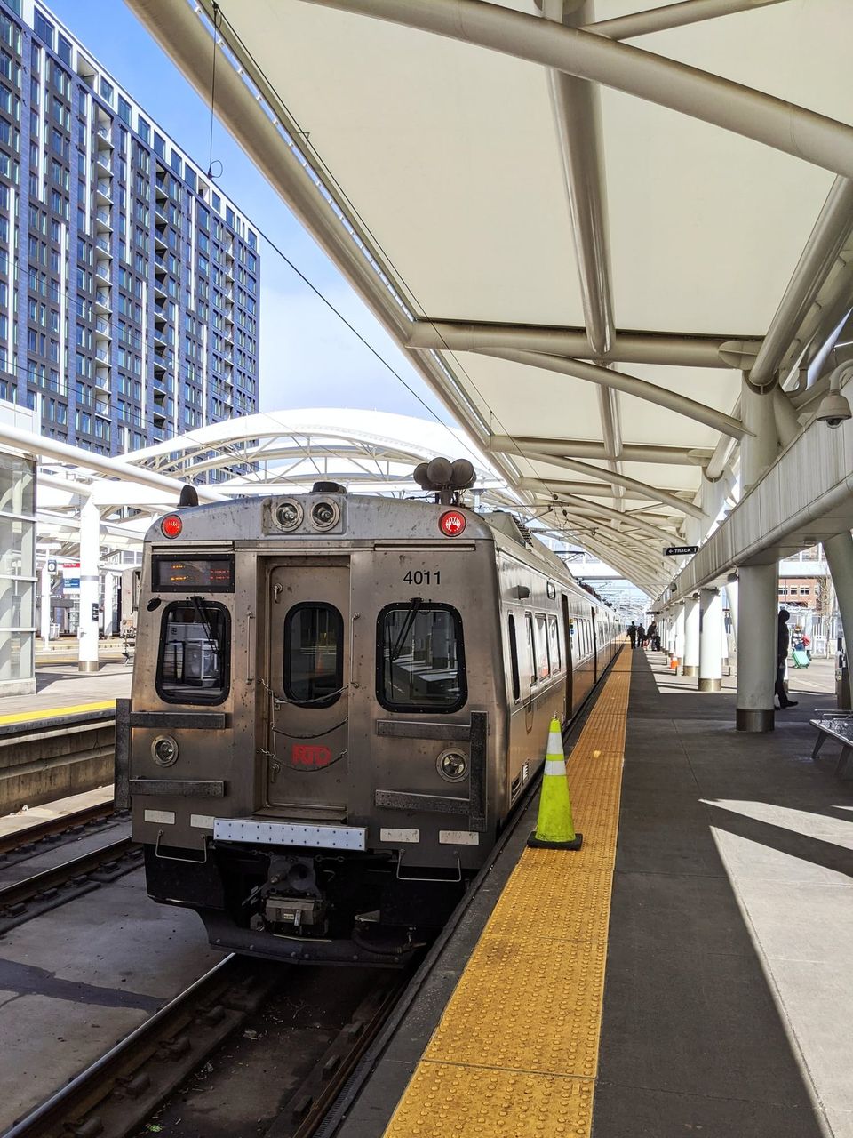 Silver RTD commuter train 4011 under the white canopy at Denver Union Station