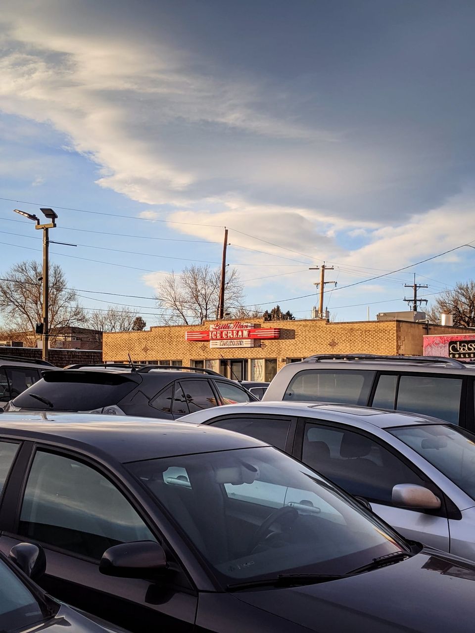 Little Man Ice Cream sign on a brick building behind a parking lot under a dramatic sky
