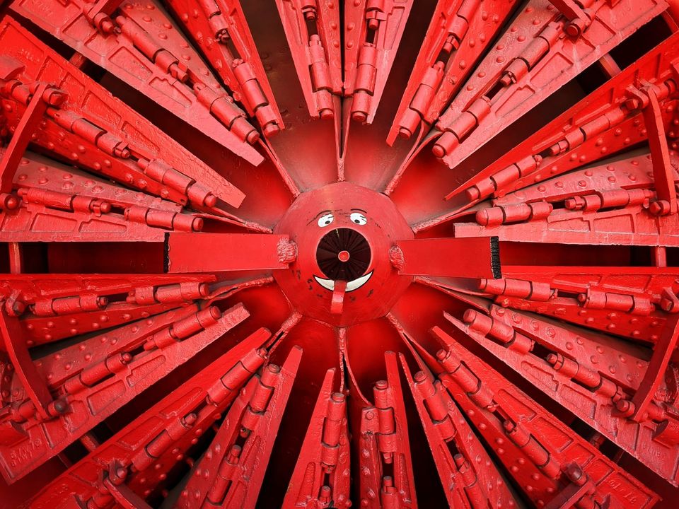 Close-up of a red rotary snowplow blade with a cartoon face painted on its hub
