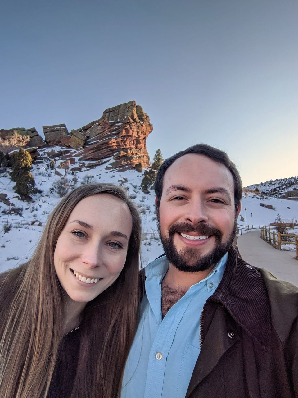 Selfie of Sam and a woman with light-brown hair in front of snowy red rock formations