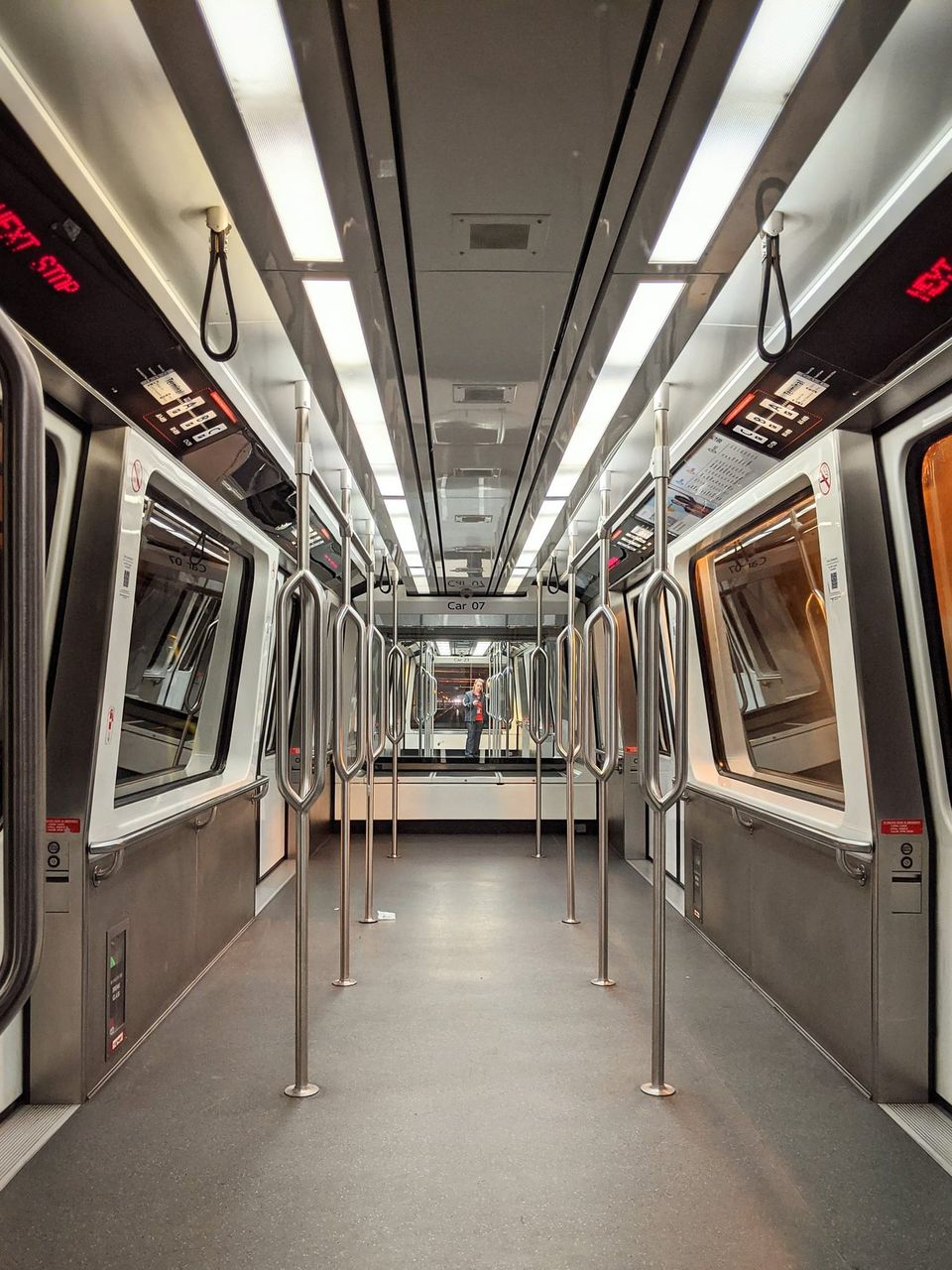 Empty airport train car with steel poles and red Next Stop signs