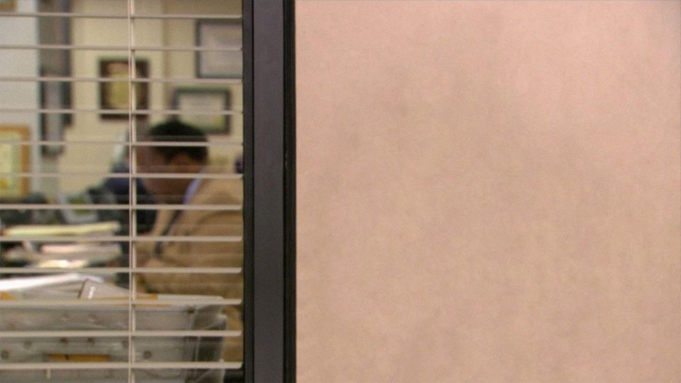 Zoom background of The Office aside room with a man at a desk seen through window blinds