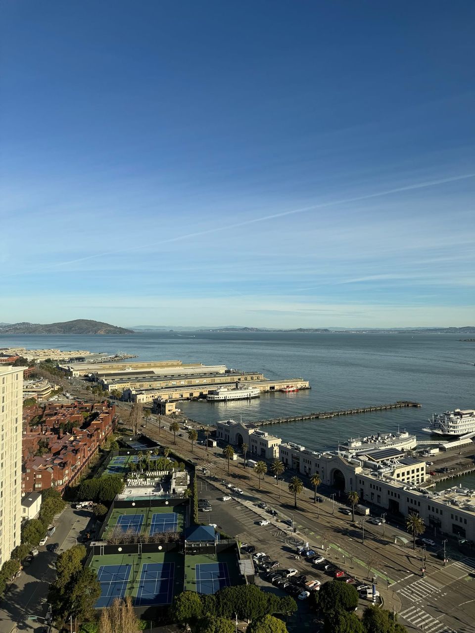 Aerial view of San Francisco's waterfront piers, the Embarcadero and tennis courts with the bay beyond