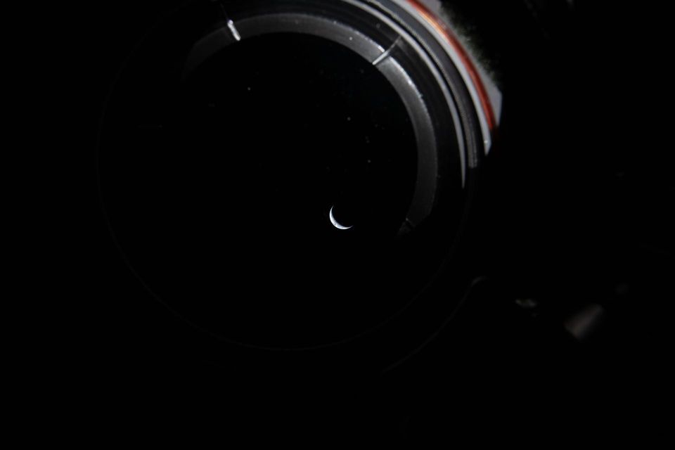 Tiny crescent Earth seen through a dark spacecraft window