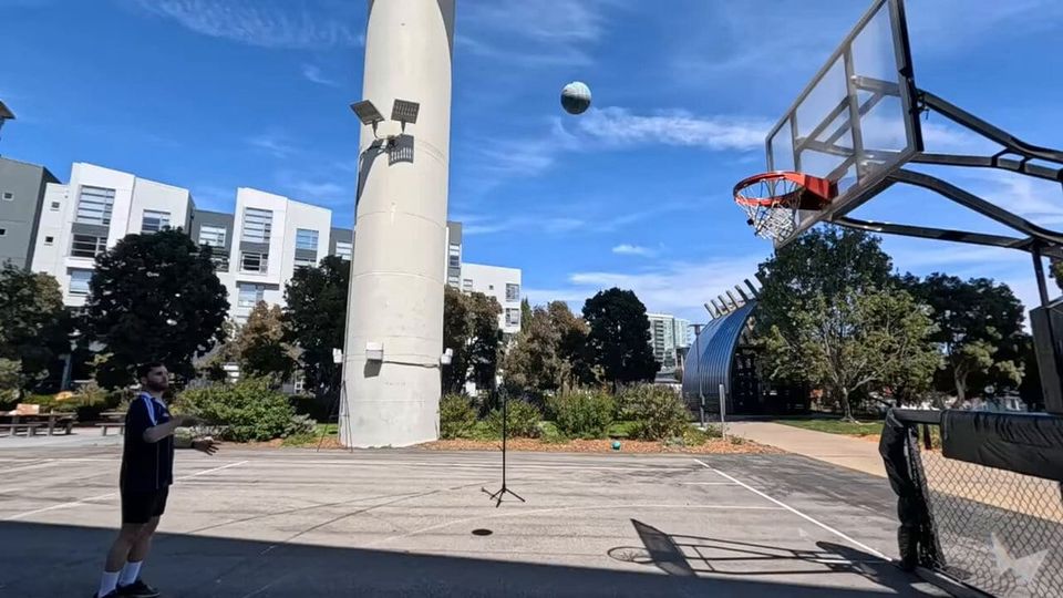 Man shooting a basketball toward a hoop on an outdoor court, the ball mid-air against a blue sky