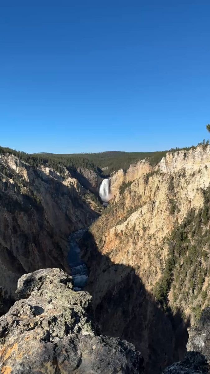 Grand Canyon of the Yellowstone seen from a rocky overlook with the distant waterfall and river below