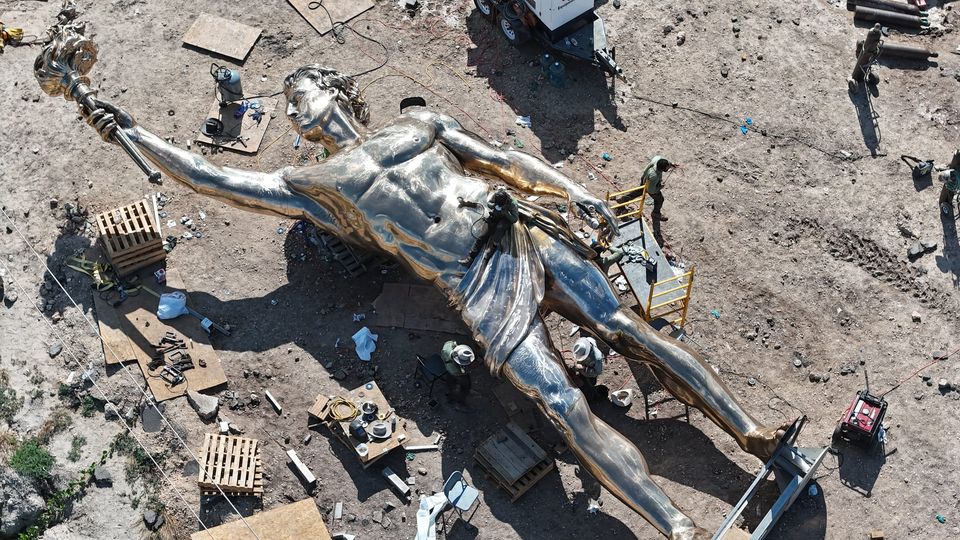 Aerial view of the bronze Prometheus statue surrounded by workers and equipment at the worksite
