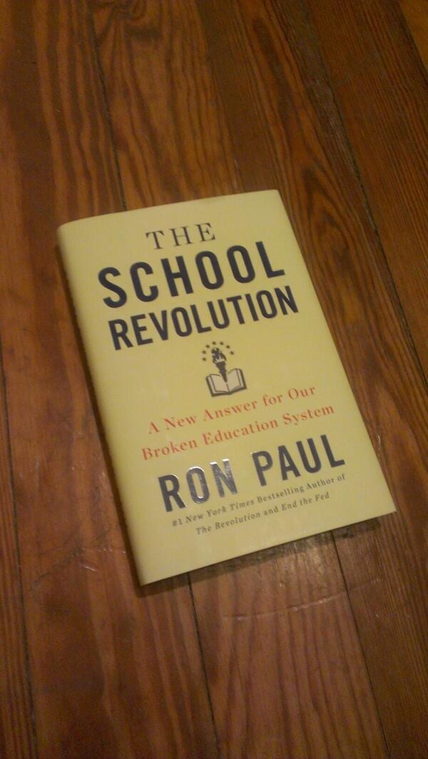 Copy of The School Revolution by Ron Paul, subtitled A New Answer for Our Broken Education System, on a wood floor