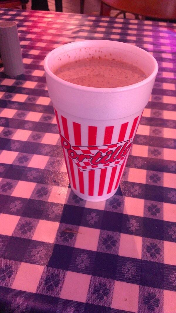 Portillo's chocolate cake shake in a red-striped foam cup on a checkered tablecloth