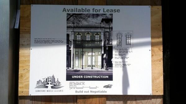 Available for Lease sign on plywood with a rendering of a two-story storefront labeled Under Construction