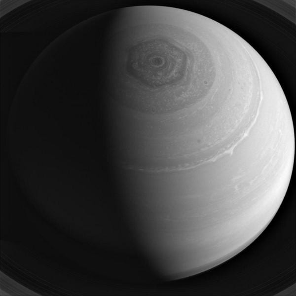 Grayscale view of Saturn's north pole with a hexagon-shaped storm pattern around a central vortex