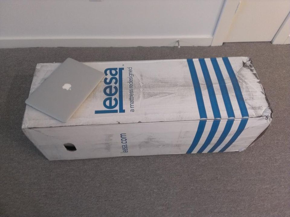 MacBook Air lying on a long Leesa mattress box on carpet for scale