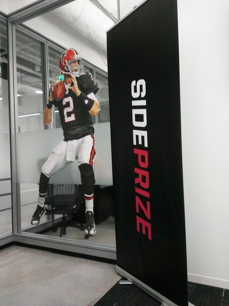 Life-size Falcons quarterback wall decal in jersey 2 on office glass beside a black SidePrize banner
