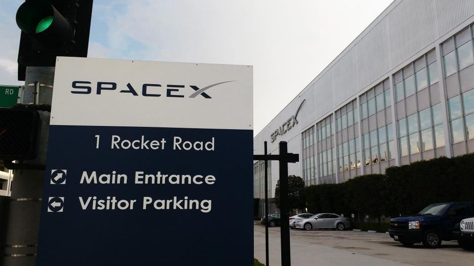 SpaceX sign reading 1 Rocket Road, Main Entrance and Visitor Parking in front of the SpaceX headquarters building
