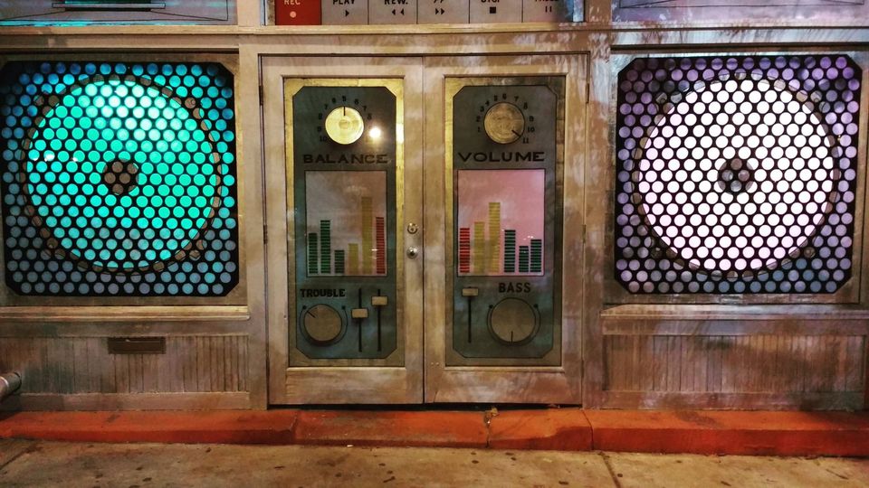 Building facade painted as a stereo with glowing teal and purple speaker windows and doors labeled Balance and Volume