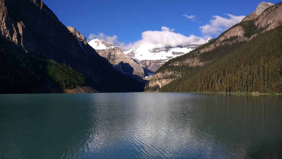 Turquoise Lake Louise leading to snow-capped peaks and a glacier under a blue sky