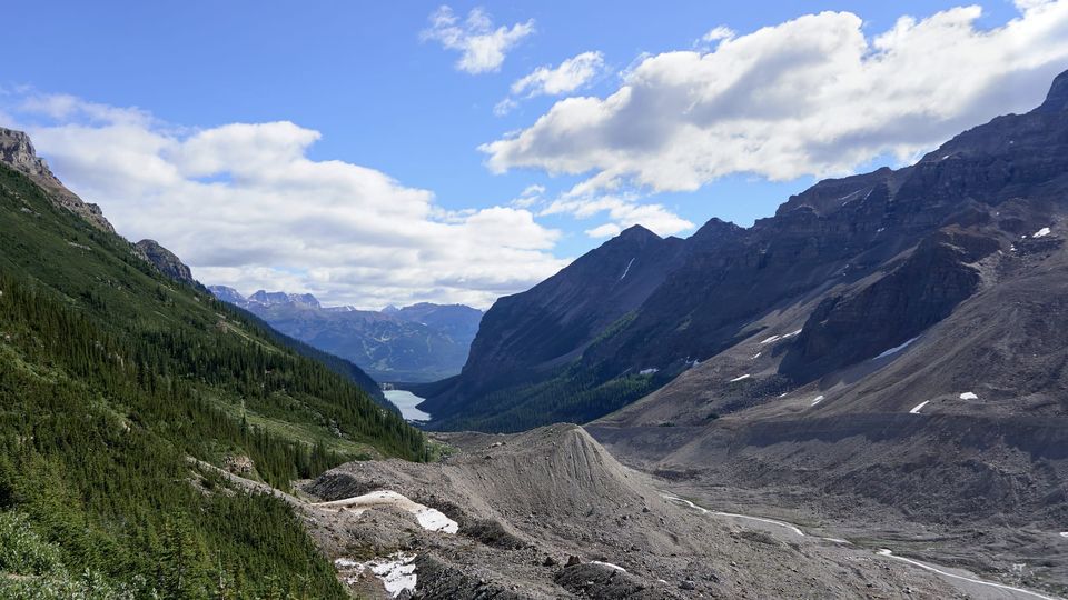 Glacial valley of gray moraine and forest leading to a turquoise lake between mountains