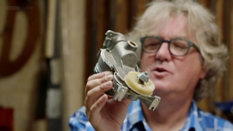 Gray-haired man in glasses and a plaid shirt holding up an appliance motor with a pulley, BBC Four HD logo