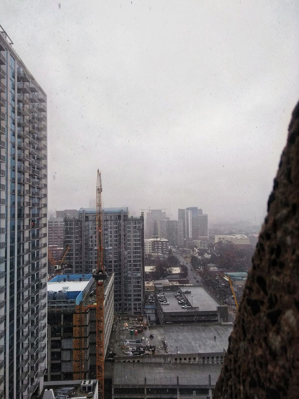 Snow falling over Midtown Atlanta high-rises and an orange construction crane under gray skies