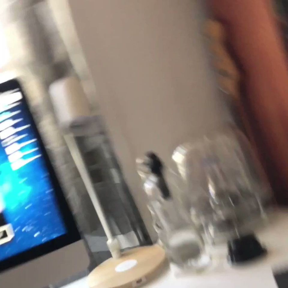 Blurry photo of a desk with an iMac, a clear water bottle and a wooden stand
