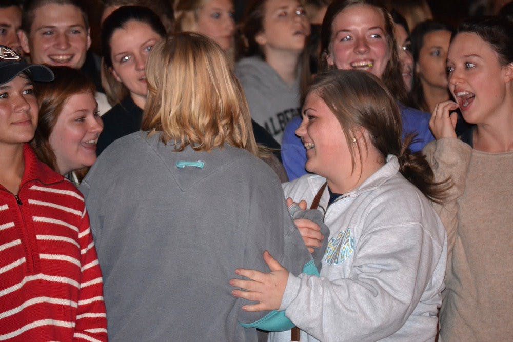 A crowd of young women laughing and reacting with excitement at an indoor event